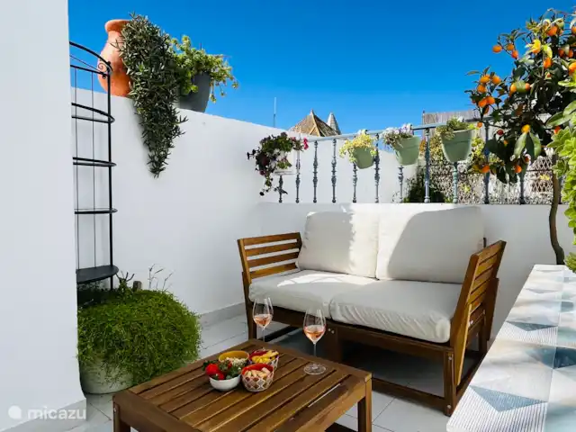Privé terras met tweezits bankje, tafel en stoel.
